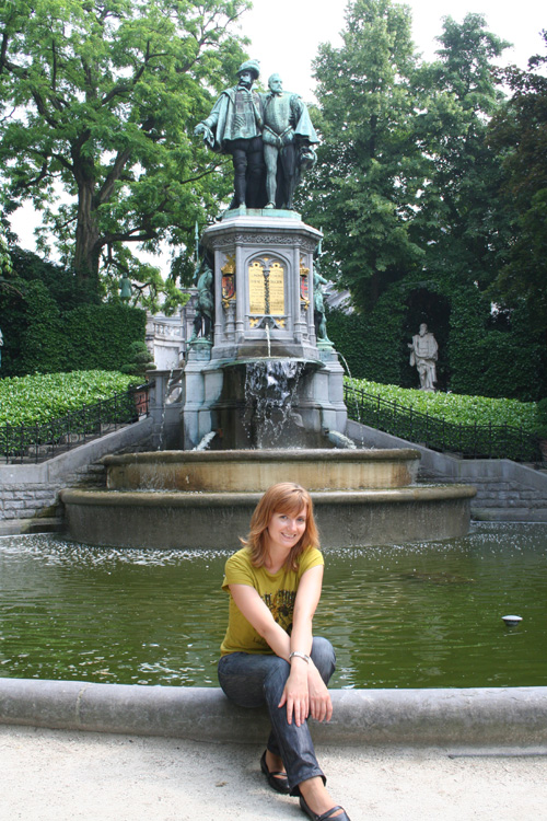 Iwona sitting in front of a fountain at Place du Petit Sablon